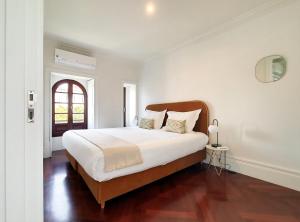 - une chambre blanche avec un grand lit et une fenêtre dans l'établissement Trindade Premium Apartments, à Porto