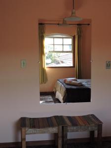 a mirror in a bedroom with a bed and a window at Casa Rô in Tiradentes