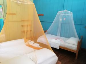 2 camas en una habitación con dosel en Eware Refugio Amazonico, en Puerto Nariño
