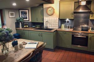 a kitchen with green cabinets and a wooden table at CELYN - SNOWDONIA COTTAGE in Caernarfon +7 photos