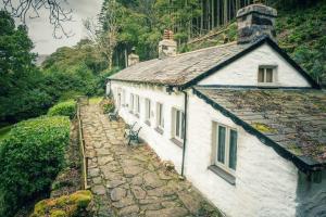 a white building on a stone path next to a house at CELYN - SNOWDONIA COTTAGE in Caernarfon