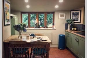 a kitchen with a wooden table and some windows at CELYN - SNOWDONIA COTTAGE in Caernarfon