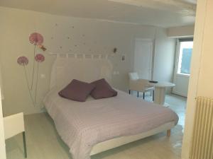 Schlafzimmer mit einem Bett mit lila Kissen und einem Tisch in der Unterkunft Chambres d'Hôtes Selon Morphee in Selongey