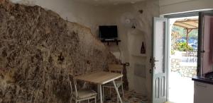 L'Incanto di Cala Feola في بونسا: طاولة وكراسي في غرفة بجدار حجري