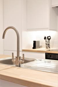 a kitchen with a stainless steel sink and white cabinets at Frederick Place - Your Apartment in Bristol