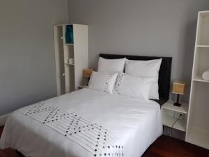 ein Schlafzimmer mit einem weißen Bett mit weißer Bettwäsche und Kissen in der Unterkunft ARCHITECTs VIEW - SUIT 2 in Durban