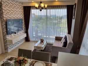 a living room with a large window and a tv at Execlusive Seaview 1 bedroom suite with toproof pool at The Patio Bangsaen in Ban Bang Saen (1)