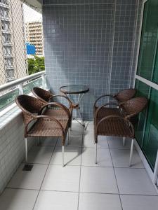 un balcón con sillas de mimbre y mesas en un edificio en Beach Class, en Fortaleza