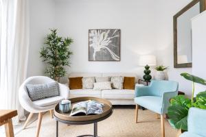 a living room with a white couch and chairs at Genteel Home Mateos Gago in Seville
