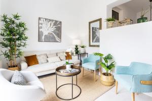 a living room with a white couch and blue chairs at Genteel Home Mateos Gago in Seville