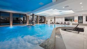 a large swimming pool with clouds in a hotel at Evita Hotel & SPA in Tleń