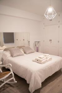 ein weißes Schlafzimmer mit 2 Betten und einer Leuchte in der Unterkunft Apartamento turístico Calle San Basilio 6 patios in Córdoba
