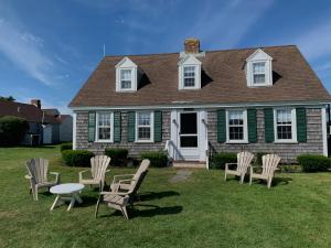 a group of chairs and a table in front of a house at Lighthouse Inn Cape Cod in West Dennis