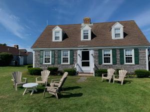 een groep stoelen en een tafel voor een huis bij Lighthouse Inn Cape Cod in West Dennis