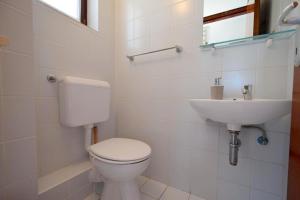 a white bathroom with a toilet and a sink at Apartment Zdenka in Njivice +13 photos