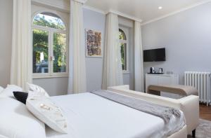 a white bedroom with a large bed and windows at Villa Natalia Luxury Rooms in Verona