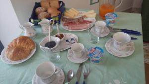 einen Tisch mit Tassen und Untertassen und ein Tablett mit Essen in der Unterkunft B&B L ORTENSIA in Bolsena