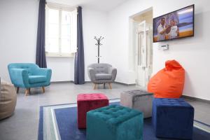 a living room with chairs and a tv on the wall at AM Hostel in Sliema