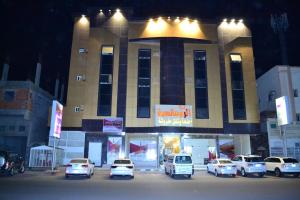 a parking lot in front of a building with parked cars at Durat Al Ruwmansiya 3 in Tabuk