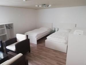 a white room with two beds and a chair at Appartement Borsum in Harsum