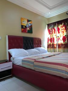 a bedroom with a bed with a red head board at Pulville Boulevard in Lagos
