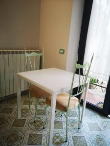 uma mesa branca e cadeiras num quarto com uma janela em B&B L ORTENSIA em Bolsena