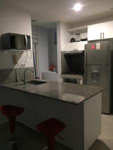 a kitchen with a counter and a refrigerator and stools at Morros Epic piso 9 in Cartagena de Indias