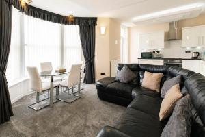 a living room with a black leather couch and a table at Burbage Holiday Lodge Apartment 3 in Blackpool