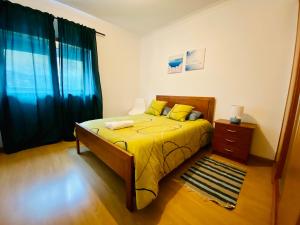 a bedroom with a bed with yellow sheets and a window at Apartamento Coselhas Coimbra in Coimbra