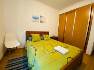a bedroom with a yellow bed and a chair at Apartamento Coselhas 2 in Coimbra