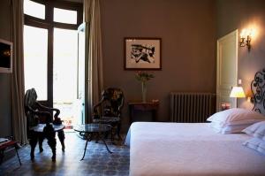 a bedroom with a bed and chairs and a window at Grand Hôtel Nord-Pinus in Arles