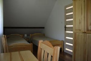 two beds in a room with a table and a cabinet at Domek Uherce Mineralne in Uherce Mineralne (7)