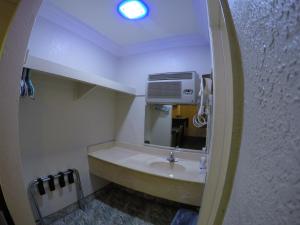 Baño pequeño con lavabo y espejo en Calico Motel, en Anaheim