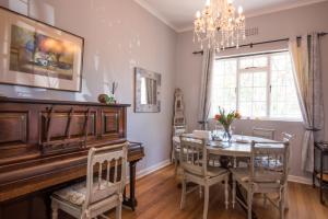 ein Esszimmer mit einem Tisch und einem Klavier in der Unterkunft Greenlawns B&B in Kapstadt