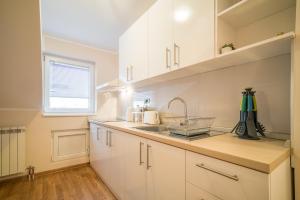 a kitchen with white cabinets and a sink and a window at Skadarlija City Break in Belgrade