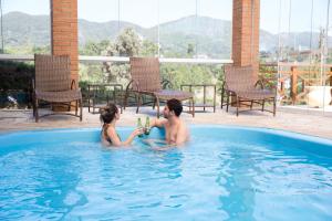 a man and woman playing in a swimming pool at Pousada Suiça Mineira Centro in Monte Verde