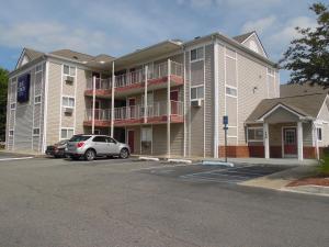 a apartment building with a car parked in a parking lot at InTown Suites Extended Stay Valdosta GA in Valdosta