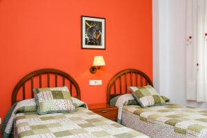 2 camas en una habitación con paredes de color naranja en Pensión Numancia, en Madrid