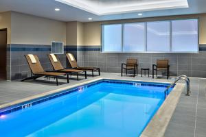- une piscine dans une chambre d'hôtel avec des chaises et une table dans l'établissement Hyatt Place Grand Rapids Downtown, à Grand Rapids