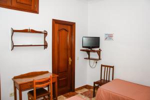 Habitación con cama, escritorio y TV. en Pensión Numancia, en Madrid