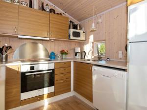 a kitchen with wooden cabinets and white appliances at 6 person holiday home in Knebel in Ørby