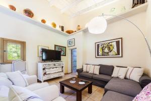 Una sala de estar con un sofá y un televisor. en Villa Cuxac De Na Joana, en Pollensa