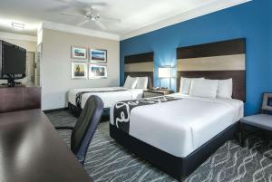 a hotel room with two beds and a flat screen tv at La Quinta by Wyndham Phoenix I-10 West in Phoenix