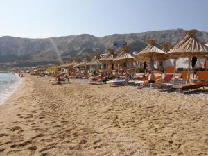 a beach with chairs and umbrellas and people on it at Villas Corinthia in Baška