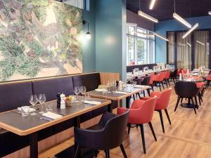 a restaurant with tables and chairs and a large painting at Mercure Paris Saint-Ouen in Saint-Ouen