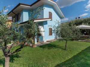 a blue house with trees in front of it at Appartamento Bella Cora in Lazise