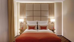 a bedroom with a large bed with two lamps at Hotel Wegner - T h e culinary art hotel in Hannover