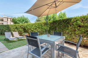 a table with chairs and an umbrella on a patio at Residencial Llenaire in El Port