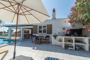 an umbrella on a patio next to a pool at Villa Estrella Fugaz in Binibeca