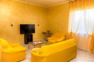 Sala de estar amarilla con 2 sillas amarillas y TV en Villa Nino, en Petacciato